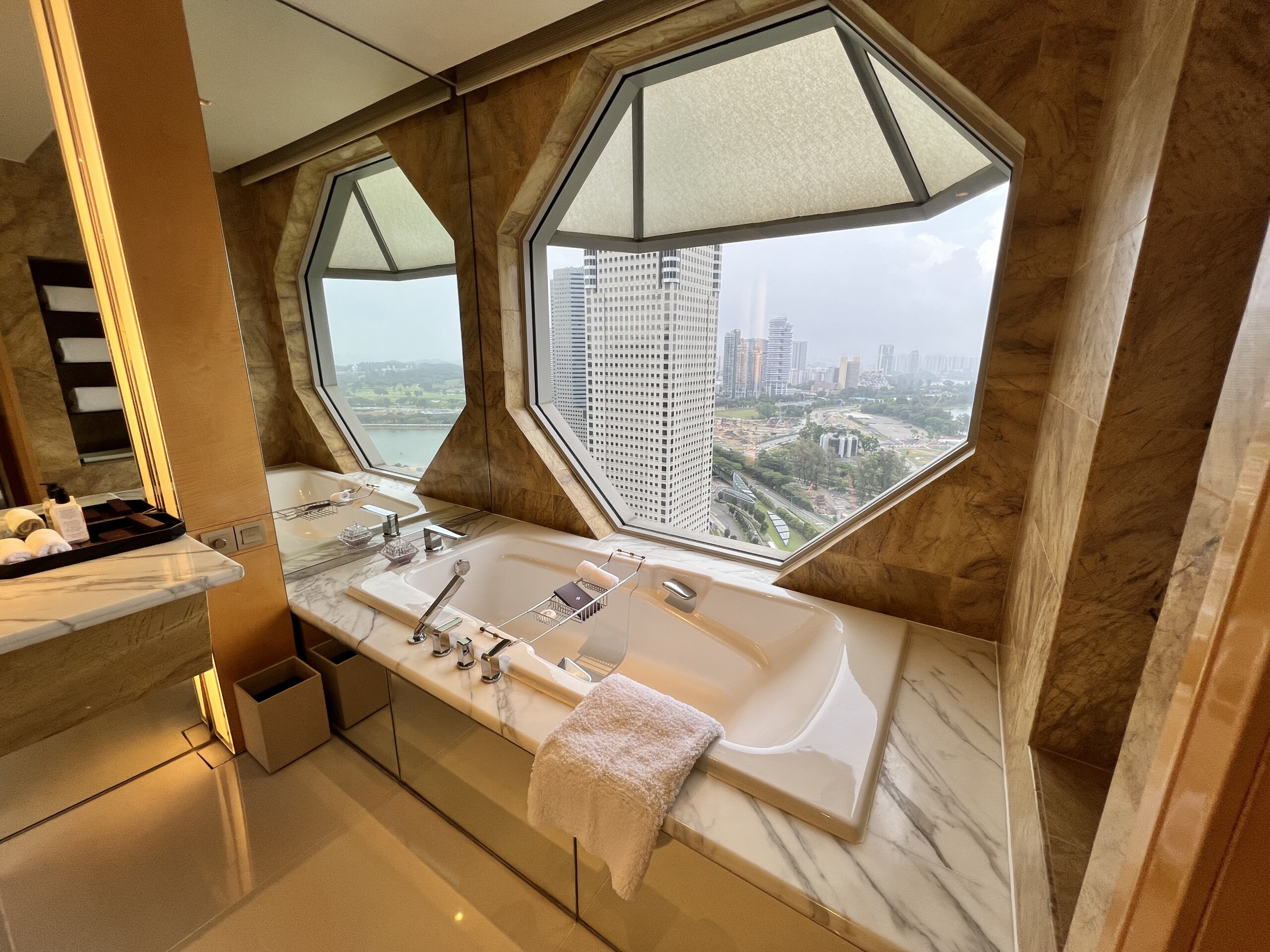 八角形の窓が特徴的なバスルーム。大理石の洗面台とバスタブ