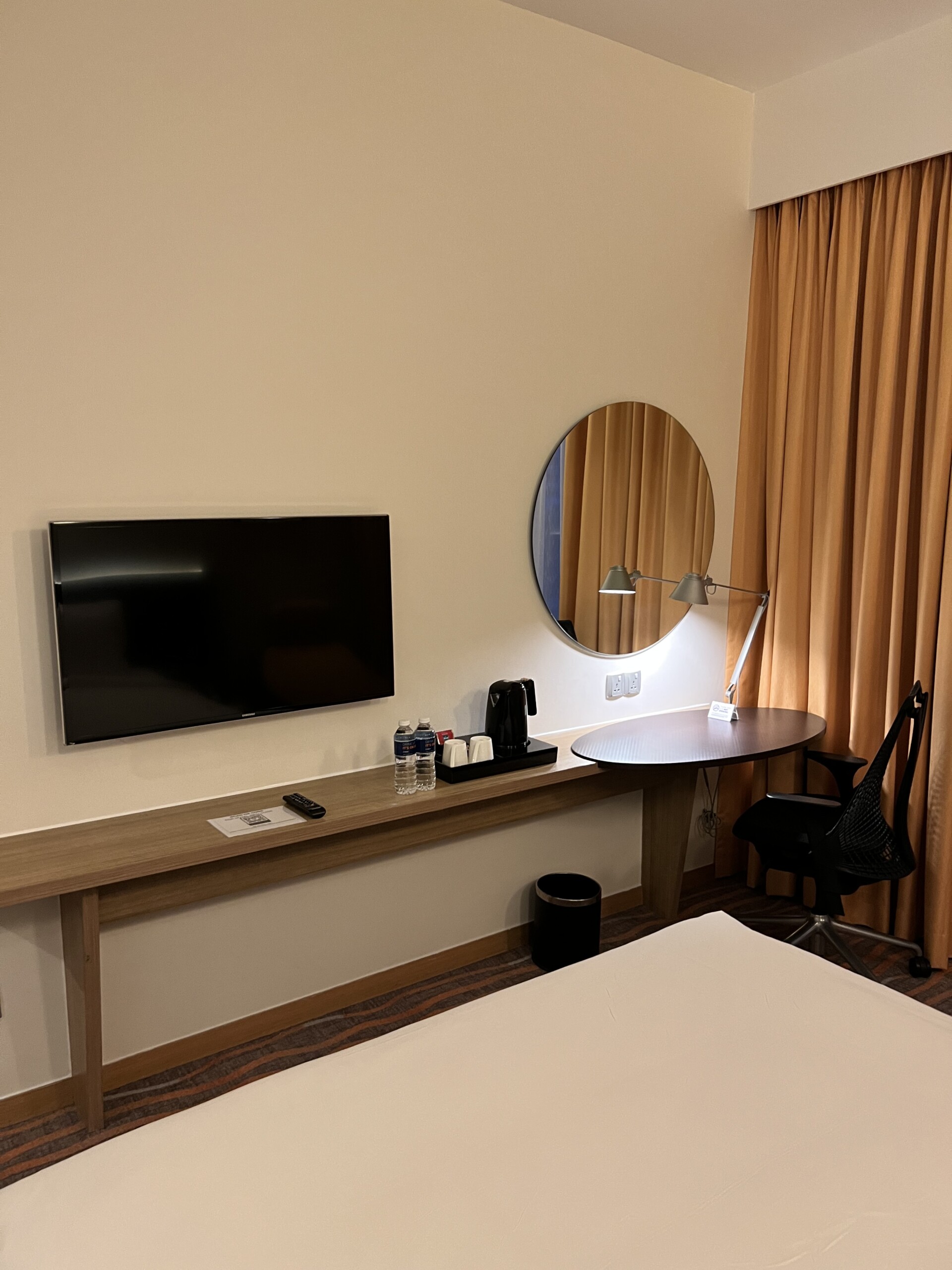 客室のデスクエリア。大型テレビと楕円形ミラー、コーヒーメーカーを完備