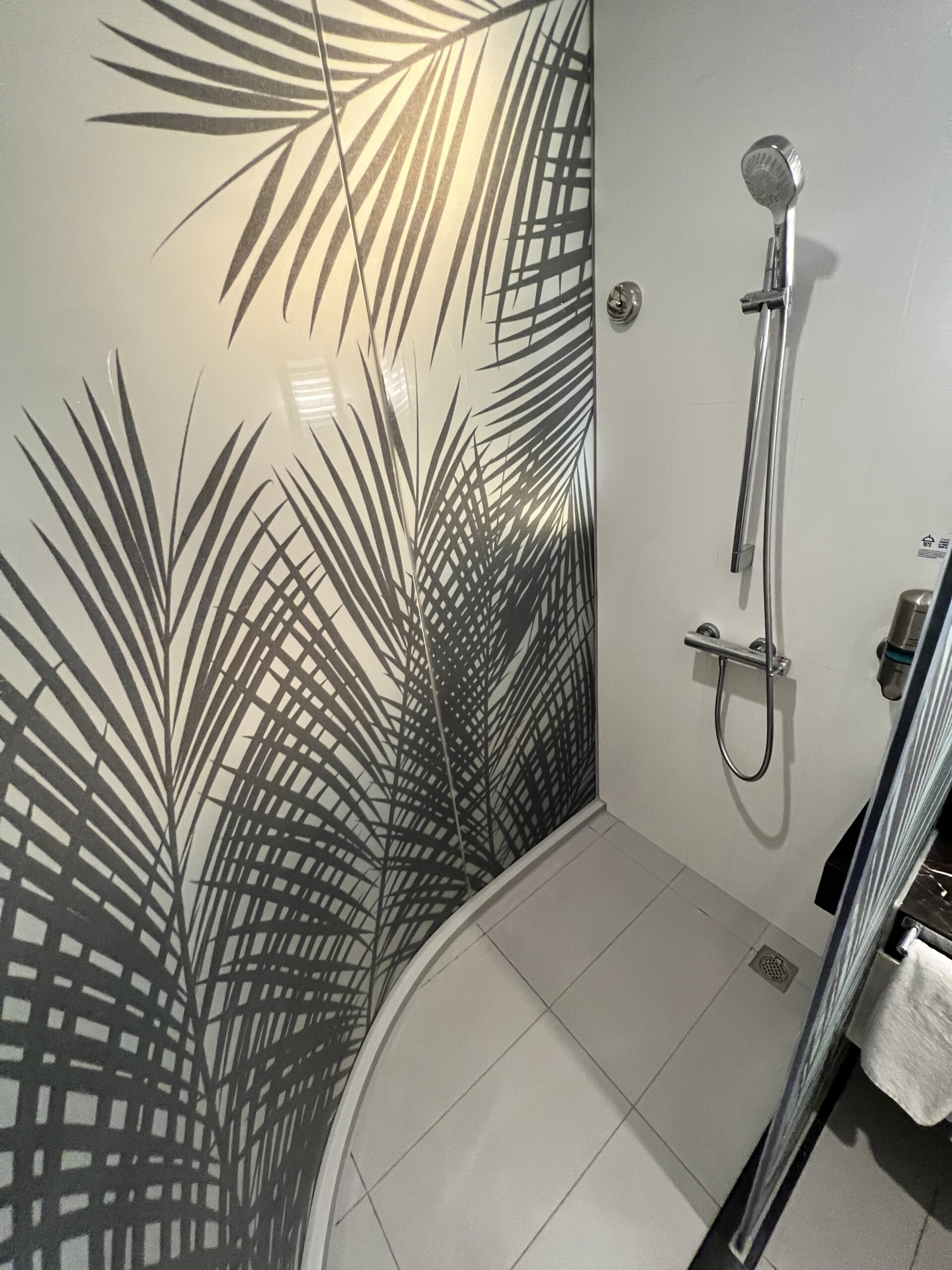 シャワーブースの壁面にはボタニカル柄のアートが施され、リゾート感を演出