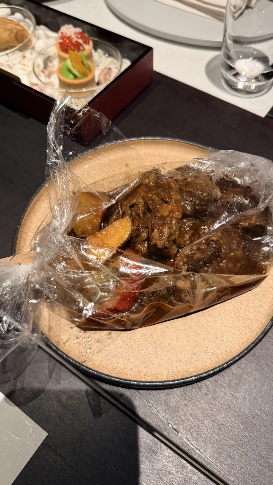 透明な袋に入った肉や野菜の料理を皿に載せた星のや沖縄の客室夕食