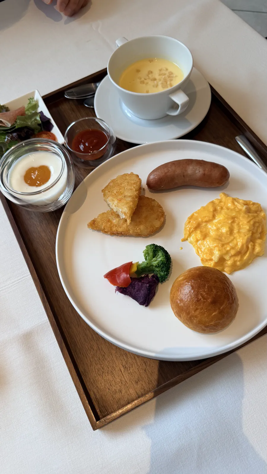丸い皿にパンや卵、ソーセージを盛り、スープを添えたダイニングの子ども用朝食