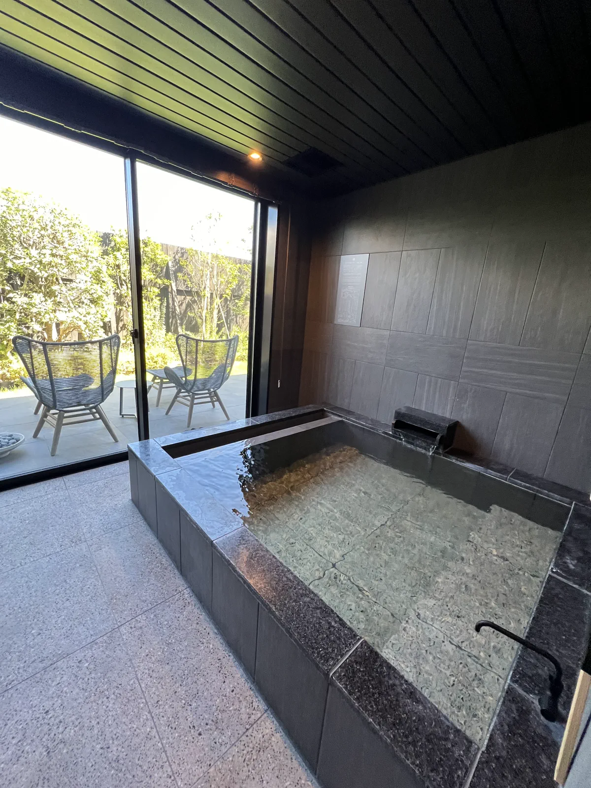 窓の外にテラス席が見える、広々とした客室露天風呂。開放感あふれるプライベートな湯浴み。