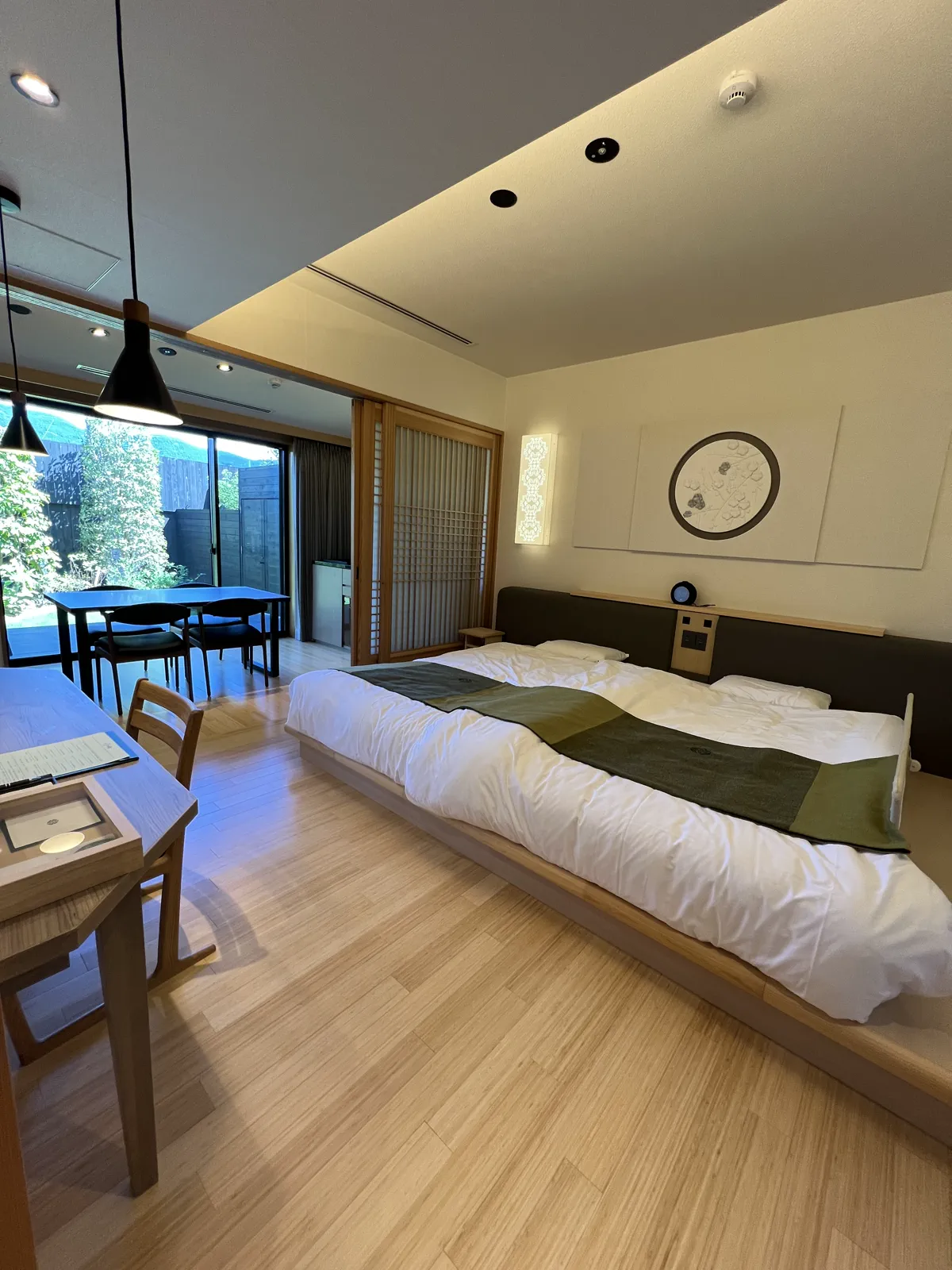 旅館の広々とした客室。大きなベッドと窓の外に広がる庭園が魅力。