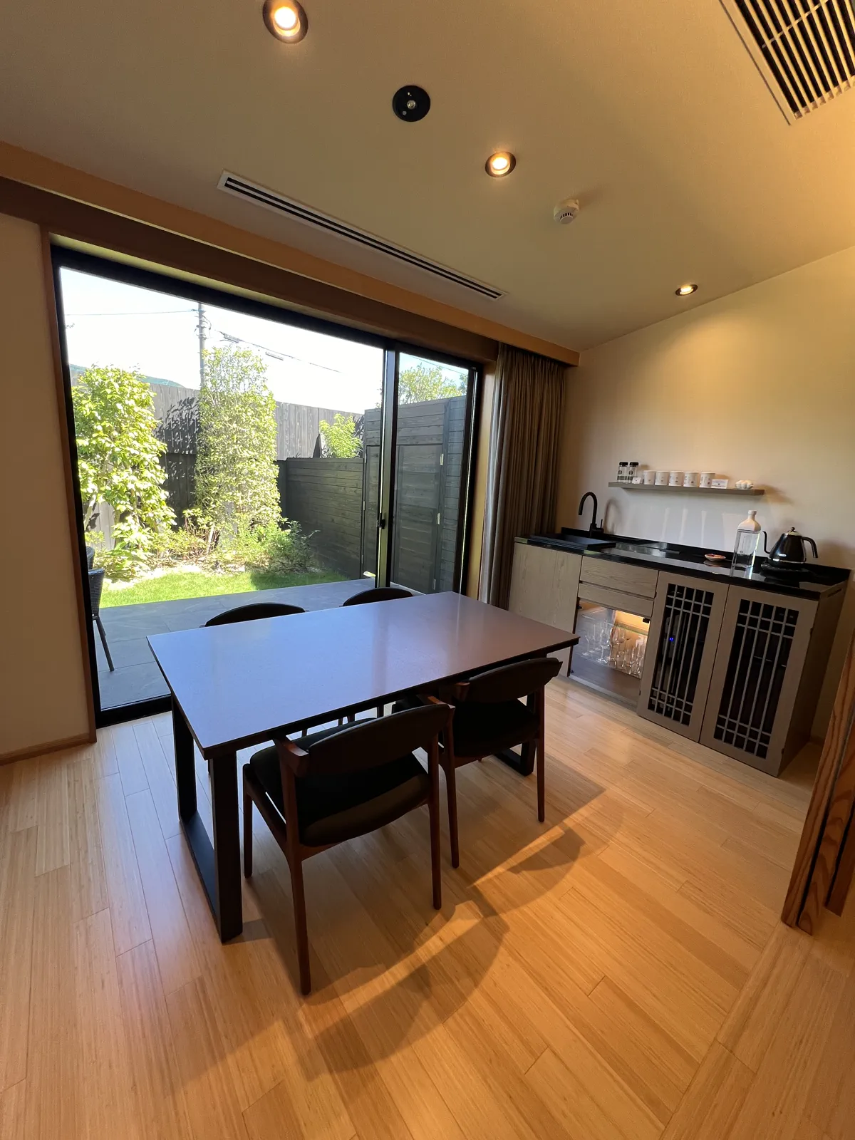 旅館の客室にあるダイニングスペースとミニバー。窓からは美しい庭園が望める。