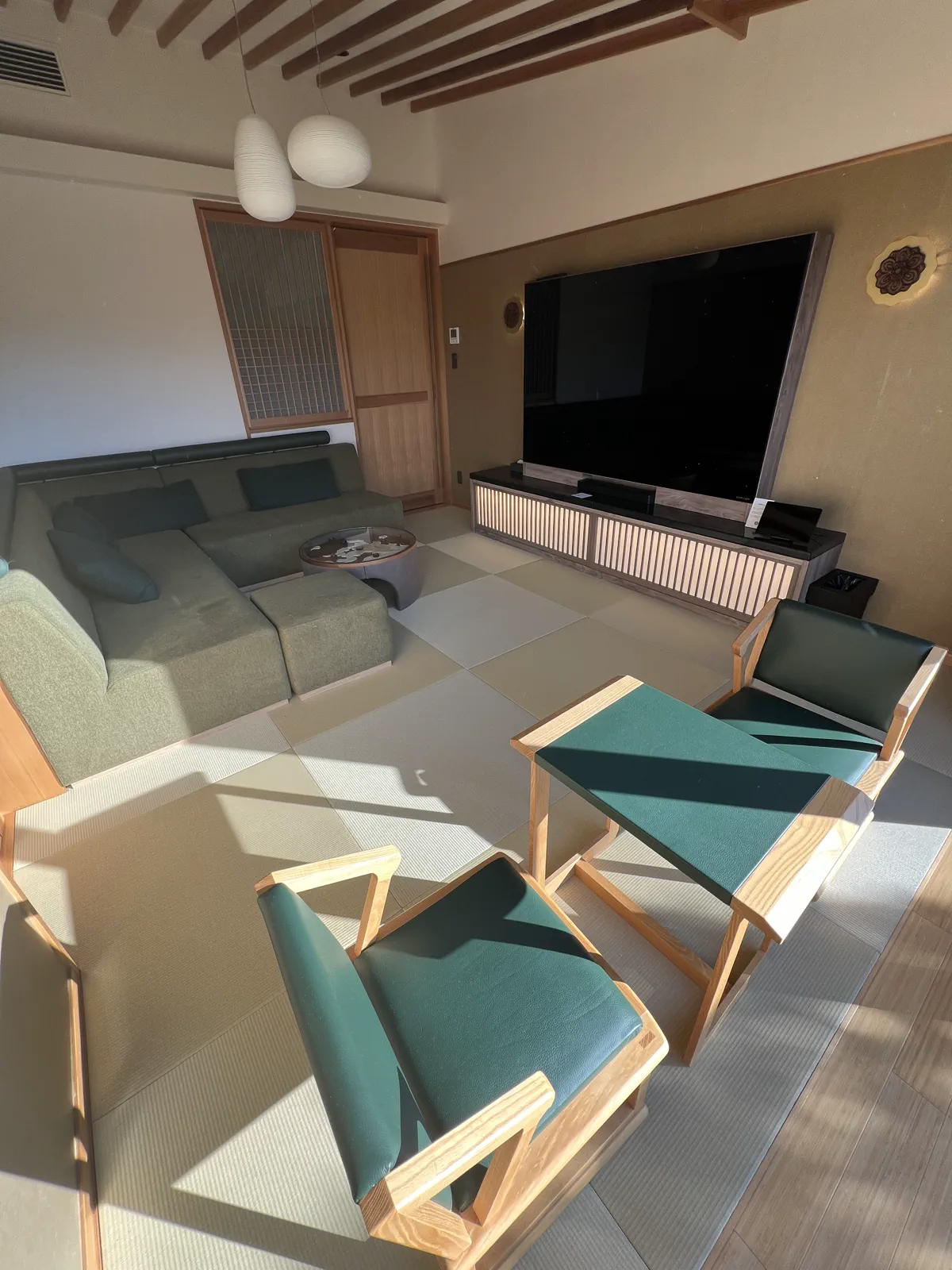 畳敷きの和モダンな客室リビング。大型テレビとL字ソファが備えられている。