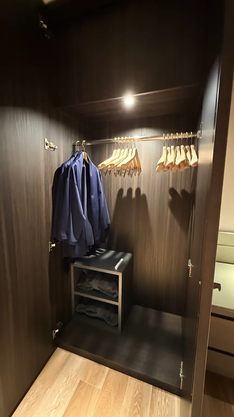 ホテルのクローゼット、ハンガーにかけられた服と棚にタオル