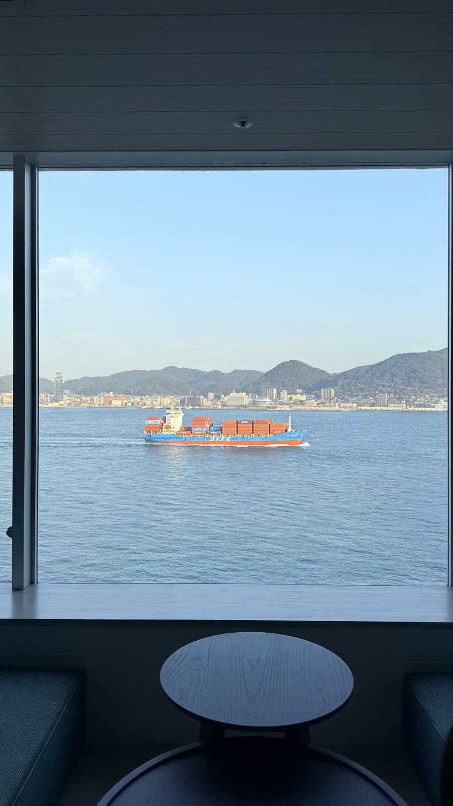 客室の窓枠越しに見える関門海峡の大きな貨物船